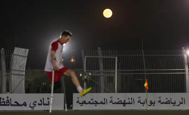 The full moon rises above a player during the final of Syria's first football tournament for people with disabilities at Al-Muhafaza Stadium in Damascus, Syria, Wednesday, July 29, 2026. (AP Photo/Ghaith Alsayed)