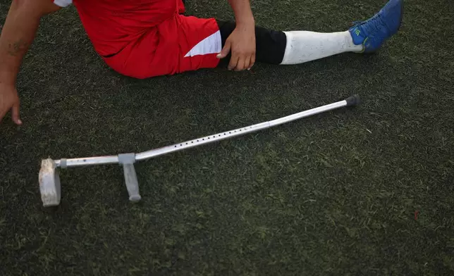 A player stretches beside a crutch before the final of Syria's first football tournament for people with disabilities at Al-Muhafaza Stadium in Damascus, Syria, Wednesday, July 29, 2026. (AP Photo/Ghaith Alsayed)