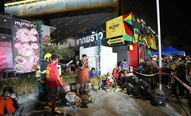 Rescuers rest after putting out a fire in Bangkok, Thailand, Monday, July 13, 2026. (AP Photo/Sakchai Lalit)