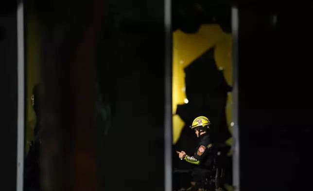 A rescuer is seen inside the site of a fire at a pub in Bangkok, Thailand, Monday, July 13, 2026. (AP Photo/Sakchai Lalit)