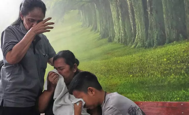 Relatives of a victim in a music bar fire cry while receiving the victim's body at a police hospital in Bangkok, Thailand, Tuesday, July 14, 2026. (AP Photo/Sakchai Lalit)