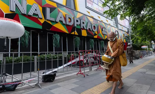 A Buddhist monk walks outside the music bar where a fire killed a number of people in Bangkok, Thailand, Tuesday, July 14, 2026. (AP Photo/Wason Wanichakorn)
