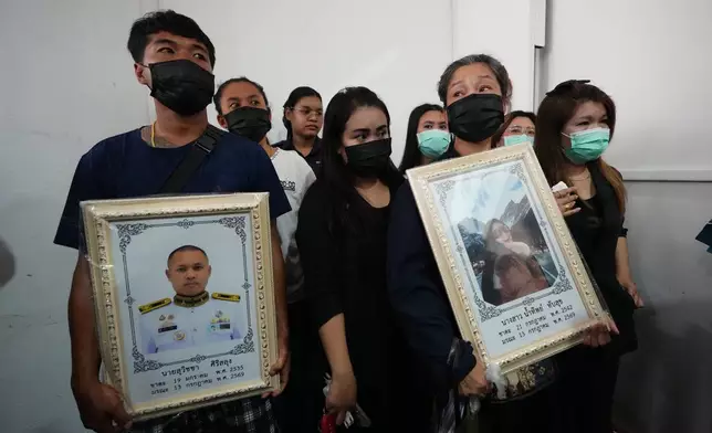 Relatives of a victim in a music bar fire hold portraits of husband Suvitcha Sirisalung and wife Namthip Tubsuk while receiving the victims' bodies at a police hospital in Bangkok, Thailand, Tuesday, July 14, 2026. (AP Photo/Sakchai Lalit)