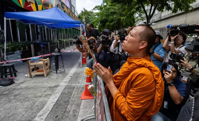 A Buddhist monk prays outside the music bar where a fire killed a number of people in Bangkok, Thailand, Tuesday, July 14, 2026. (AP Photo/Wason Wanichakorn)