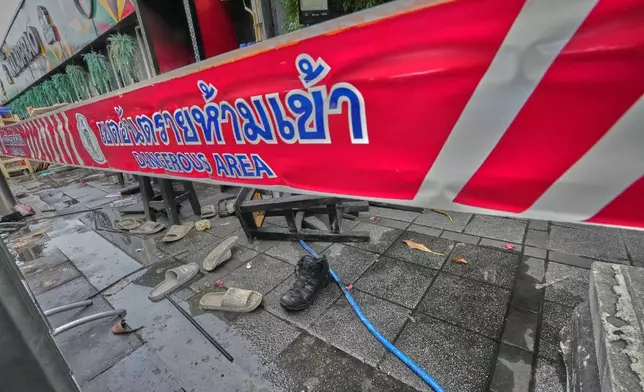 Shoes are seen scattered in front of a pub in Bangkok, Thailand, Monday, July 13, 2026, after a fire. (AP Photo/Sakchai Lalit)