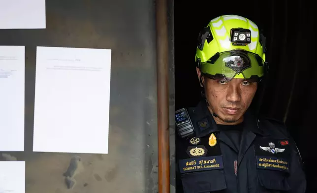 A rescuer looks on at the entrance door of the music bar where a fire killed a number of people in Bangkok, Thailand, Tuesday, July 14, 2026. (AP Photo/Wason Wanichakorn)