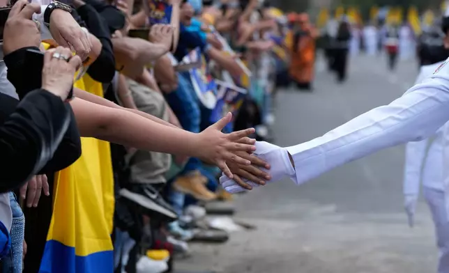 A navy cadet touches hands with spectators watching the Independence Day military parade in Bogotá, Colombia, Monday, July 20, 2026. (AP Photo/Fernando Vergara)