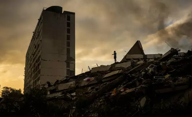 A man stands atop a mountain of rubble three days after twin earthquakes struck, in La Guaira, Venezuela, Saturday, June 27, 2026. (AP Photo/Matias Delacroix)