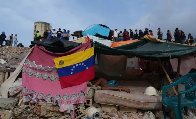 A young man sleeps as rescue workers continue searching through the rubble after the earthquakes in La Guaira, Venezuela, Saturday, July 4, 2026. (AP Photo/Ariana Cubillos)