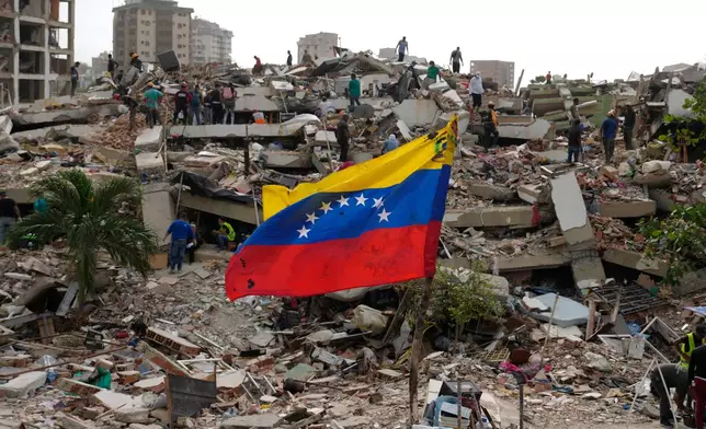 Residents and rescue workers search through the rubble of buildings damaged in the earthquakes that struck La Guaira, Venezuela, Thursday, July 2, 2026. (AP Photo/Ariana Cubillos)