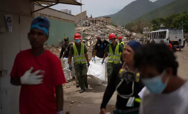 Rescue workers and forensic technician Joel Mirabal, back left, recover the body of an earthquake victim in La Guaira, Venezuela, Tuesday, June 30, 2026. (AP Photo/Matias Delacroix)