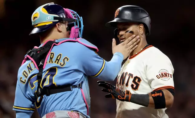 Milwaukee Brewers catcher William Contreras (24) playfully slaps San Francisco Giants' Luis Arraez, right, during the seventh inning of a baseball game in San Francisco, Monday, July 27, 2026. (AP Photo/Jed Jacobsohn)