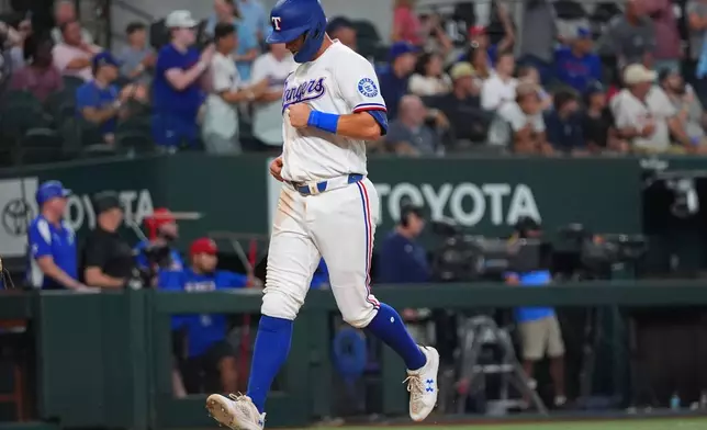 Texas Rangers' Josh Jung scores on a double by teammate Jake Burger during the third inning of a baseball game against the Chicago White Sox, Tuesday, July 21, 2026, in Arlington, Texas. (AP Photo/LM Otero)