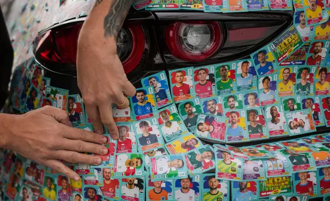 Chilean social media influencer Ariel Osses works on covering his car with World Cup soccer album stickers, at a park in Santiago, Chile, Wednesday, July 8, 2026. (AP Photo/Esteban Felix)