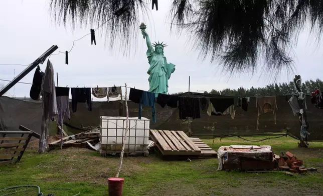 A replica of the Statue of Liberty stands behind clothes hanging to dry at a home on outskirts of Buenos Aires, Argentina, Wednesday, June 24, 2026. (AP Photo/Rodrigo Abd)