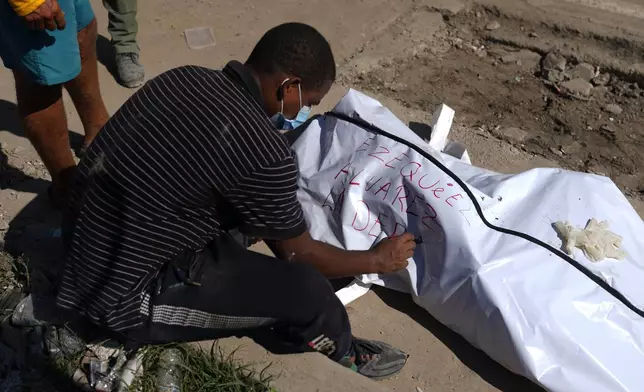 Julio Ladera writes the name of his nephew after he found his body in the debris of buildings destroyed by earthquakes in La Guaira, Venezuela, Tuesday, July 7, 2026. (AP Photo/Ariana Cubillos)