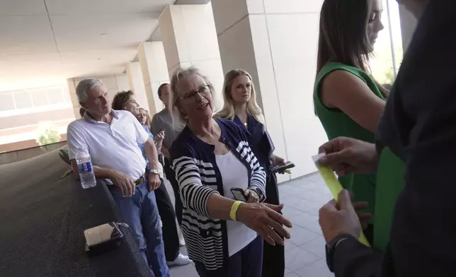 People receive wristbands to access limited public seating available at a preliminary hearing for Tyler Robinson, the Utah man accused of fatally shooting Charlie Kirk, in Provo, Utah, Wednesday, July 8, 2026. (AP Photo/Ty ONeil)