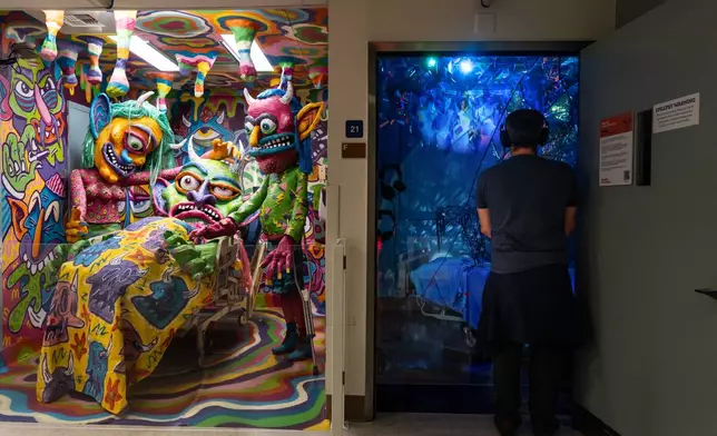 A visitor views an installation by Margüi while standing beside an installation by Guy "Dioz" Bloom during the "Hospital of Emotions" exhibition inside a former hospital building in Los Angeles, Wednesday, July 22, 2026. (AP Photo/Jae C. Hong)