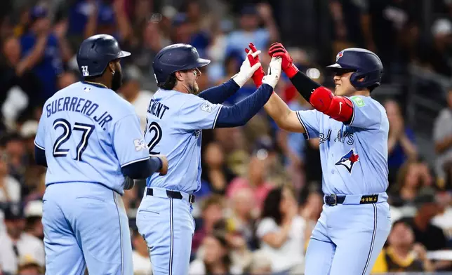 Toronto Blue Jays' Kazuma Okamoto, right, is congratulated by Ernie Clement, center, as Vladimir Guerrero Jr., left, looks on after Okamoto hit a three-run home run against the San Diego Padres in the fifth inning of a baseball game Friday, July 10, 2026, in San Diego. (AP Photo/Derrick Tuskan)