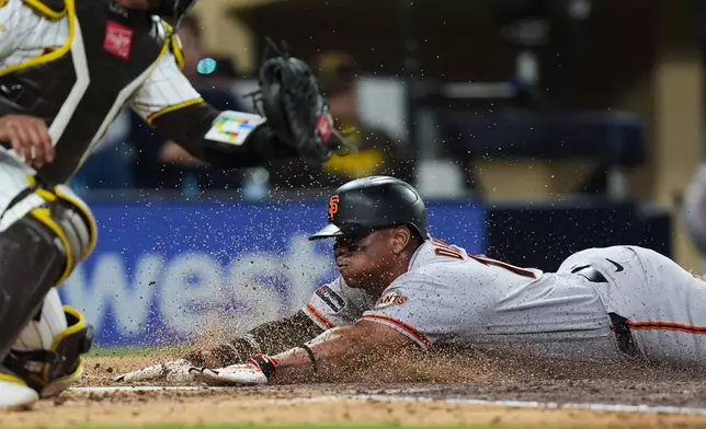 San Francisco Giants' Rafael Devers, right, slides in to score off a sacrifice fly by Daniel Susac as San Diego Padres catcher Luis Campusano is late with the tag, left,during the fifth inning of a baseball game Thursday, July 30, 2026, in San Diego. (AP Photo/Gregory Bull)