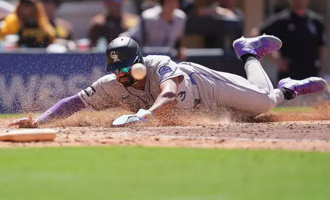 Colorado Rockies' Willi Castro slides in to score off an RBI single by Brett Sullivan during the seventh inning of a baseball game against the San Diego Padres Wednesday, July 29, 2026, in San Diego. (AP Photo/Gregory Bull)
