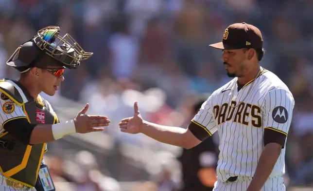 San Diego Padres pitcher Jeremiah Estrada is greeted by catcher Freddy Fermin after the third out during the eighth inning of a baseball game against the Colorado Rockies Wednesday, July 29, 2026, in San Diego. (AP Photo/Gregory Bull)