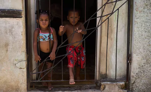 Children cool off in their doorway during a blackout in Havana, Cuba, Tuesday, July 14, 2026. (AP Photo/Ramon Espinosa)