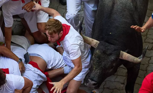 Revelers run alongside Jose Escolar's fighting bulls during the fifth running of the bulls at the San Fermín festival in Pamplona, Spain, Saturday, July 11, 2026. (AP Photo/Miguel Oses)