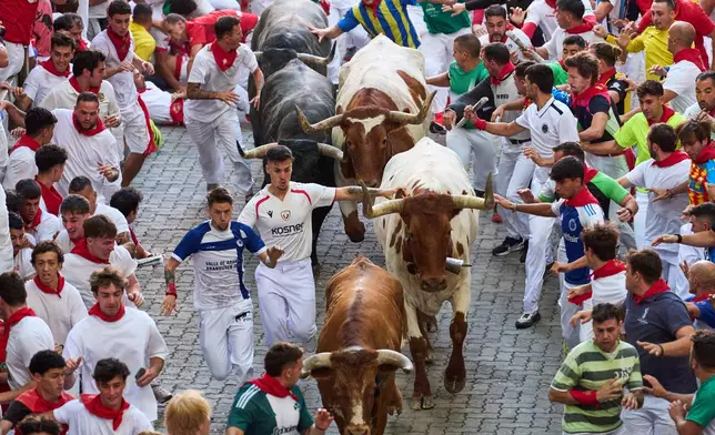Revelers run alongside Jose Escolar's fighting bulls during the fifth running of the bulls at the San Fermín festival in Pamplona, Spain, Saturday, July 11, 2026. (AP Photo/Miguel Oses)