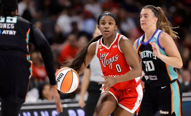 Las Vegas Aces guard Jackie Young (0) drives between New York Liberty center Jonquel Jones, left, and guard Sabrina Ionescu (20) during the first half of an WNBA basketball game Thursday, July 30, 2026, in Las Vegas. (Steve Marcus/Las Vegas Sun via AP)