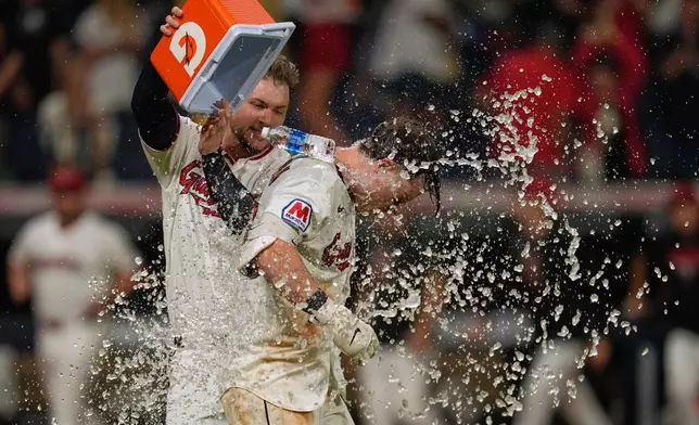 Cleveland Guardians catcher Patrick Bailey, left, douses Travis Bazzana, right, with a cooler after Bazzana hit a game winning home run in the ninth inning of the second baseball game of a split doubleheader against the Pittsburgh Pirates in Cleveland, Saturday, June 18, 2026. (AP Photo/Sue Ogrocki)