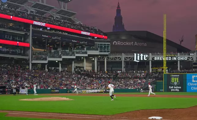 The Cleveland Guardians run off the field in the third inning of the second baseball game of a split doubleheader against the Pittsburgh Pirates as smoke filled skies return to Cleveland after rain delayed the start of the game in Cleveland, Saturday, June 18, 2026. (AP Photo/Sue Ogrocki)