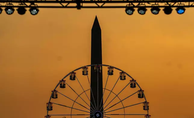 The Washington Monument and the ferris wheel on the National Mall are seen at sunset, Wednesday, July 1, 2026, on the National Mall in Washington. (AP Photo/Allison Robbert)