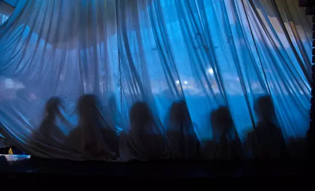 The shadows of Tibetan children are cast on a curtain as they wait to perform in a cultural program celebrating the 91st birthday of the Dalai Lama in Kathmandu, Nepal, Monday, July 6, 2026. (AP Photo/Niranjan Shrestha)