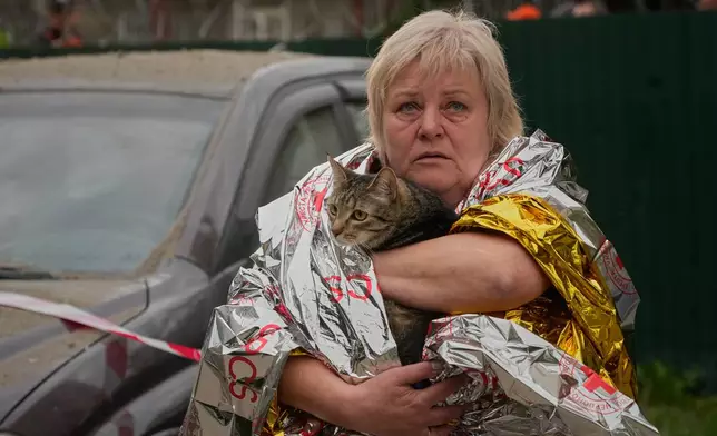 A woman carries her cat out of a damaged multistory apartment building following a Russian missile attack in Kyiv, Ukraine, Monday, July 6, 2026. (AP Photo/Efrem Lukatsky)
