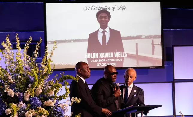 Elmore Wonsley, center, speaks next to attorney Ben Crump, left, and Rev. Al Sharpton during a memorial service for Nolan Xavier Wells, an 18-year-old found dead after taking a July 4 boat trip with friends, Monday, July 20, 2026, in Ocean Springs, Miss. (AP Photo/Gerald Herbert)