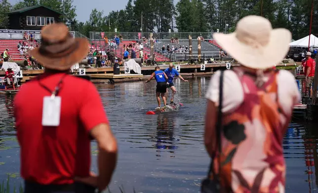 Spectators watch a men's log rolling heat during the Lumberjack World Championships, Saturday, July 18, 2026, in Hayward, Wis. (AP Photo/Ellen Schmidt)