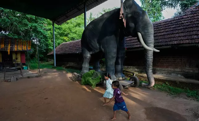 Children play next to motionless Irinjadapilly Raman, a robotic elephant, at Irinjadapilly Sree Krishna Temple in Thrissur, in the southern Indian state of Kerala, Friday, May 22, 2026. (AP Photo/Aijaz Rahi)