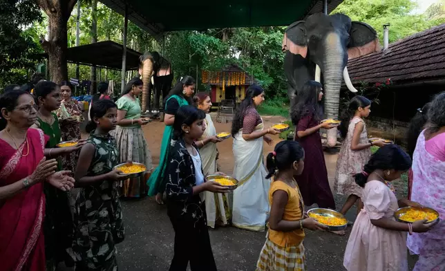A group of Hindu devotees arrive for prayers, walking past two robotic elephants at Irinjadapilly Sree Krishna Temple in Thrissur, in the southern Indian state of Kerala, Friday, May 22, 2026. (AP Photo/Aijaz Rahi)