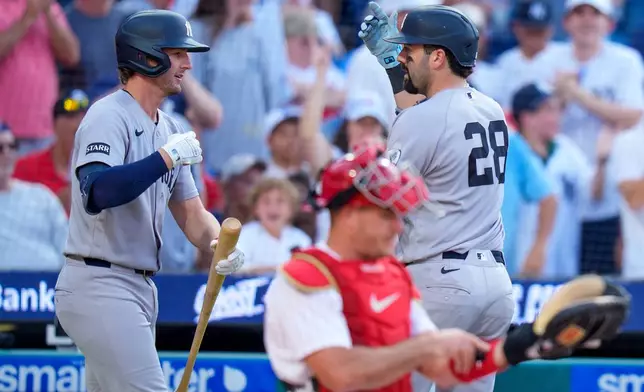 New York Yankees' Austin Wells, right, celebrates his home run with Ryan McMahon, left, as Philadelphia Phillies catcher J.T. Realmuto, center, looks over his equipment during the third inning of a baseball game, Saturday, July 25, 2026, in Philadelphia. (AP Photo/Chris Szagola)