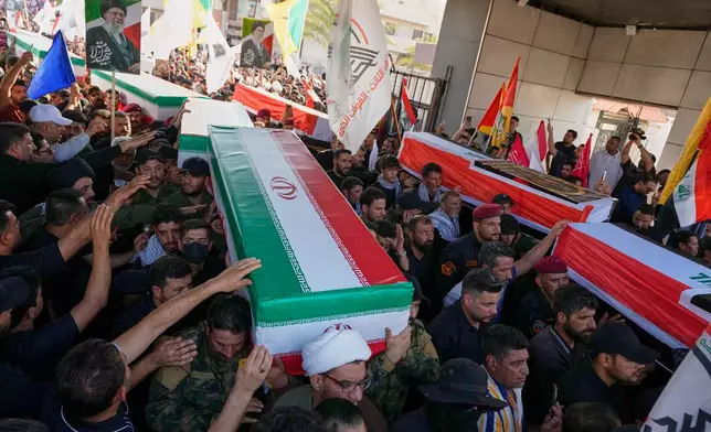 Mourners carry coffins draped in the Iranian flag, foreground, and the Iraqi flag during a group funeral for Iranian advisers and Popular Mobilization Forces fighters killed in airstrikes on bases belonging to Iraq's Popular Mobilization Forces, a coalition of predominantly Shiite militias that includes Iran-backed groups, in Mosul, Iraq, Wednesday, July 29, 2026. (AP Photo/Hadi Mizban)