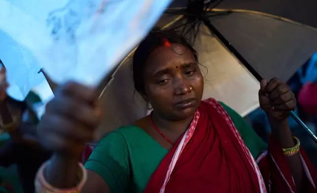Farmers and laborers shelter from the rain along a roadside after taking part in a demonstration against what they describe as exploitative lending practices by microfinance institutions, calling for the release of collateral pledged against loans and the provision of interest-free loans, in Kathmandu, Nepal, Wednesday, July 29, 2026. (AP Photo/Niranjan Shrestha)