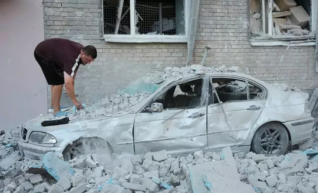 A local resident inspects a damaged car after a Russian strike on Kyiv, Ukraine, Thursday, July 2, 2026. (AP Photo/Efrem Lukatsky)