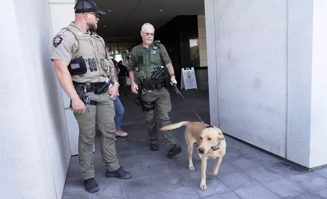 Police officials handle a dog as people access the limited public seating available at a preliminary hearing for Tyler Robinson, the Utah man accused of fatally shooting Charlie Kirk, in Provo, Utah, Wednesday, July 8, 2026. (AP Photo/Ty ONeil)