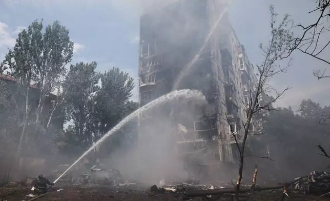 Rescue workers try to put out a fire of a residential building burning after a Russian air guided bomb strike in Zaporizhzhia, Ukraine, Tuesday, July 21, 2026. (AP Photo/Kateryna Klochko)