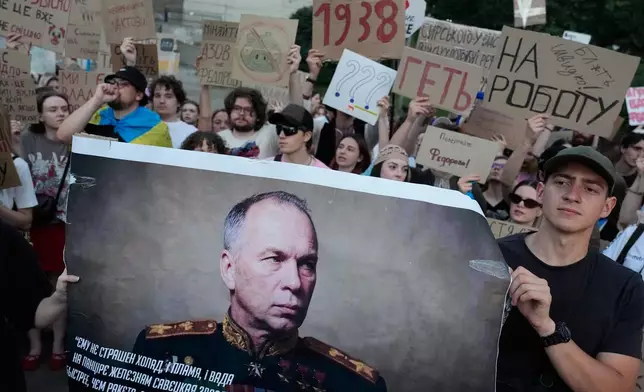 Activists hold a portrait of Ukraine's Armed Forces Commander-in-Chief Oleksandr Syrskyi demanding his resignation during a rally to denounce President Volodymyr Zelenskyy's decision to dismiss Defense Minister Mykhailo Fedorov after six months in the post, in Kyiv, Ukraine, Saturday, July 18, 2026. (AP Photo/Efrem Lukatsky)