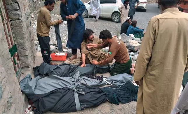 Rescue workers and volunteers cover bodies after recovering them after an overcrowded passenger bus plunged from a highway into a rocky ravine, in Dana Sar, a remote area near the border of Balochistan and Khyber Pakhtunkhwa provinces, in southwestern Pakistan, Friday, July 3, 2026. (AP Photo/Zain Ullah)