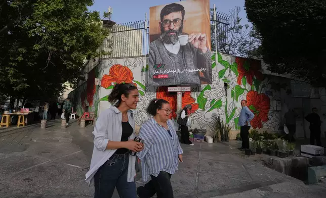 People walk past a banner which shows a portrait of slain Iranian Supreme Leader Ayatollah Ali Khamenei, ahead of his funeral ceremonies in Tehran, Iran, Thursday, July 2, 2026. (AP Photo/Vahid Salemi)
