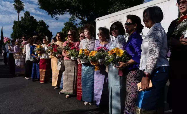 Attendees hold flowers while waiting to greet Bhikkhu Pannakara, a Buddhist monk who led a Walk for Peace from Fort Worth, Texas, to Washington, D.C., during an event at Wat Thai of Los Angeles in the North Hollywood section of Los Angeles, Monday, July 13, 2026. (AP Photo/Jae C. Hong)