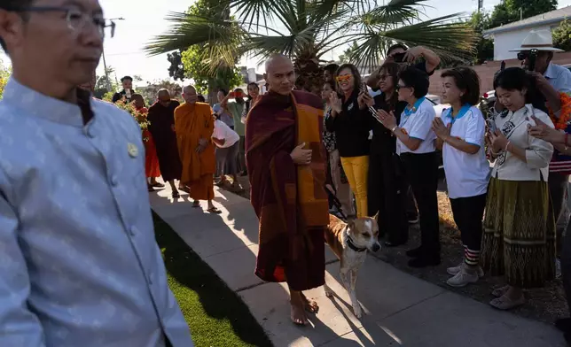 Bhikkhu Pannakara, a Buddhist monk who led a Walk for Peace from Fort Worth, Texas, to Washington, D.C., and his dog, Aloka, are greeted by well-wishers during an event at Wat Thai of Los Angeles in the North Hollywood section of Los Angeles, Monday, July 13, 2026. (AP Photo/Jae C. Hong)